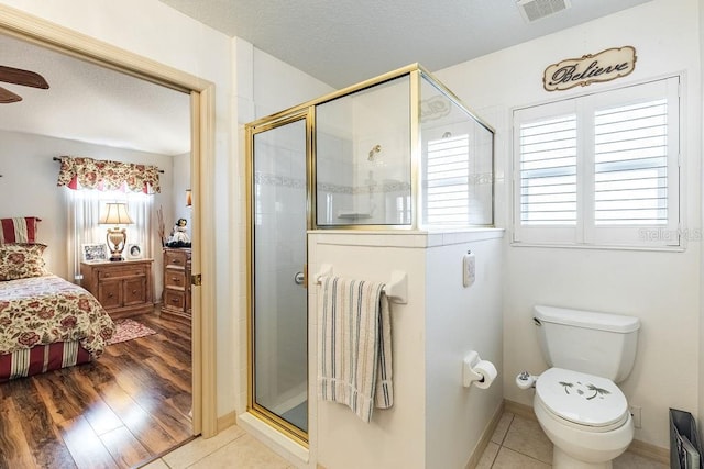 bathroom featuring tile patterned flooring, toilet, and walk in shower