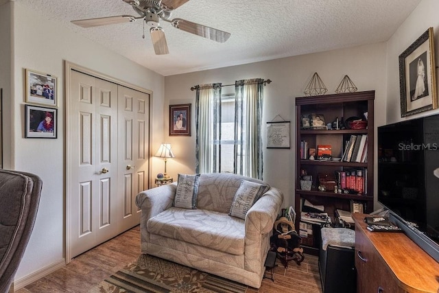 sitting room with ceiling fan, wood-type flooring, and a textured ceiling