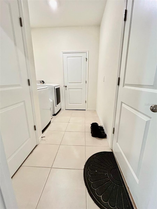 laundry area with laundry area, baseboards, washer and clothes dryer, and light tile patterned flooring