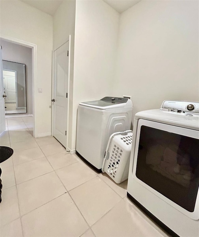 laundry room featuring laundry area, light tile patterned flooring, independent washer and dryer, and baseboards