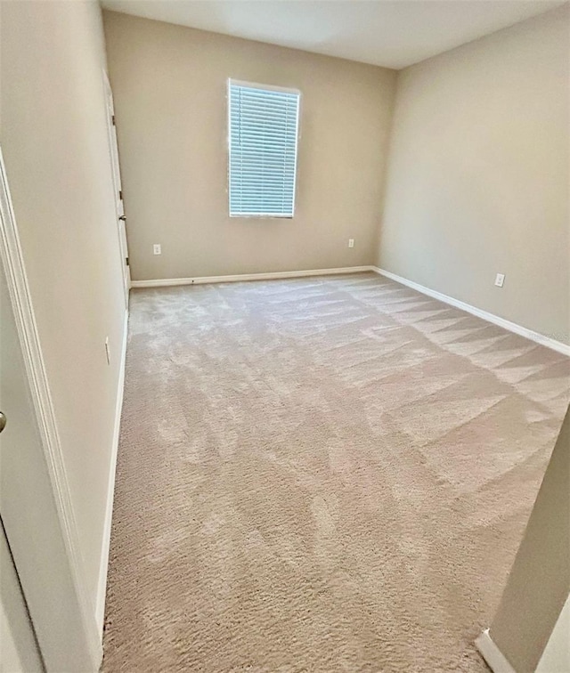 spare room with light carpet and baseboards