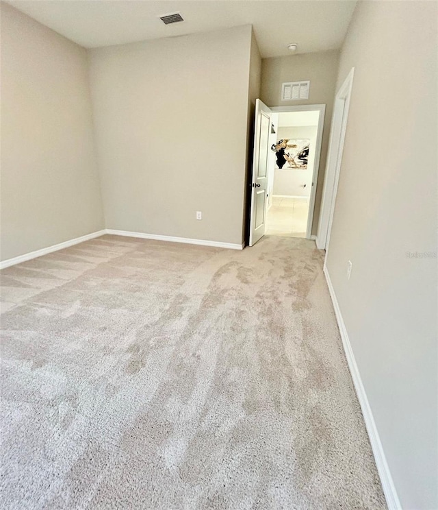 empty room featuring light carpet, visible vents, and baseboards