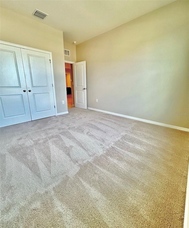 unfurnished bedroom with baseboards, a closet, visible vents, and carpet flooring