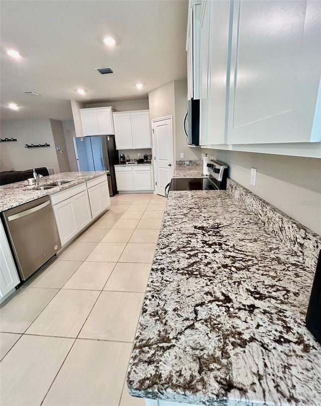 kitchen featuring visible vents, light stone counters, stainless steel appliances, a sink, and light tile patterned flooring