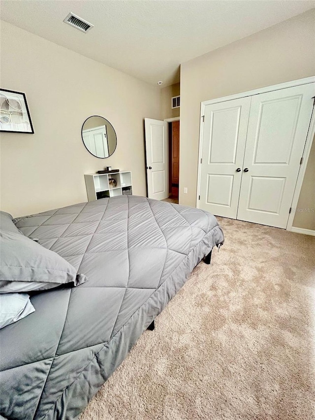 carpeted bedroom with a closet and visible vents