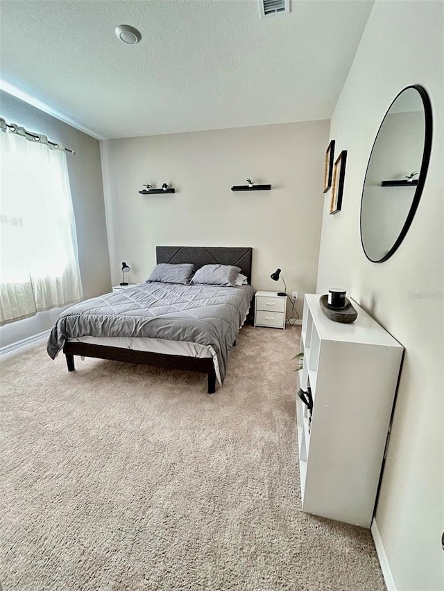 bedroom featuring a textured ceiling, visible vents, and light colored carpet