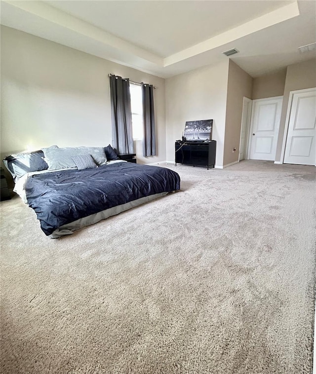 bedroom with carpet floors, baseboards, visible vents, and a tray ceiling