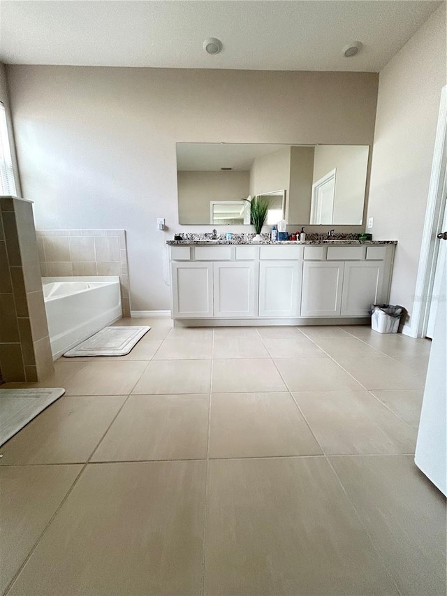 bathroom with double vanity, a garden tub, baseboards, and tile patterned floors