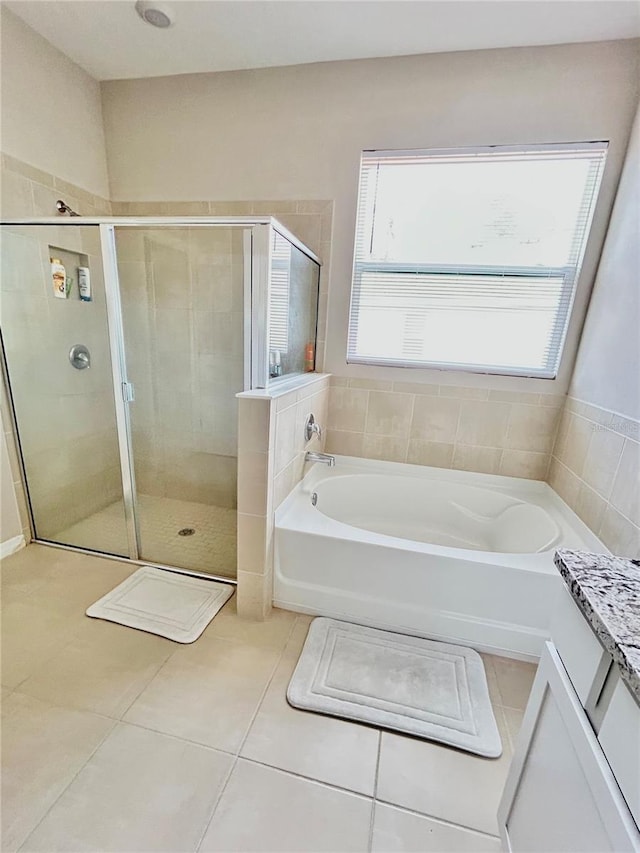 bathroom featuring a stall shower, tile patterned flooring, and a bath