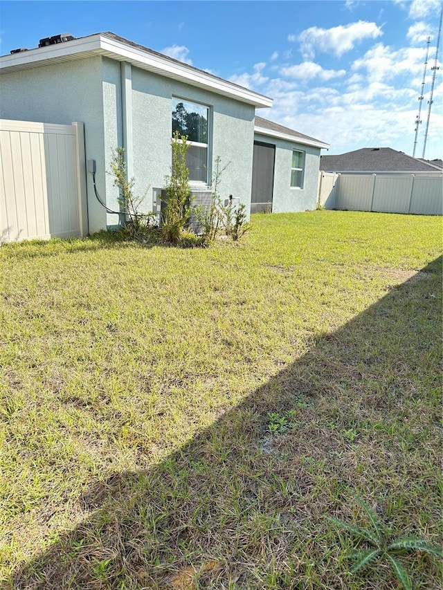 back of property with a yard, fence, and stucco siding