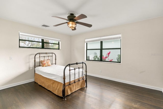 bedroom featuring a ceiling fan, visible vents, dark wood finished floors, and baseboards