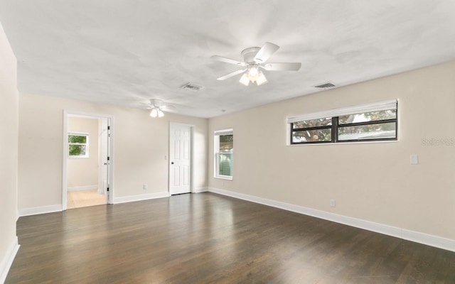 spare room with a ceiling fan, baseboards, visible vents, and dark wood-style flooring