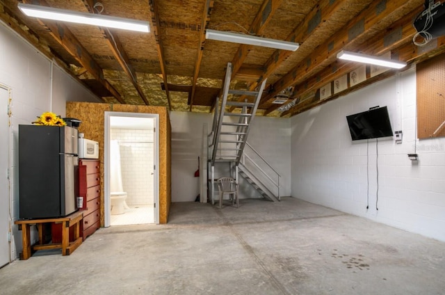 garage featuring concrete block wall and freestanding refrigerator