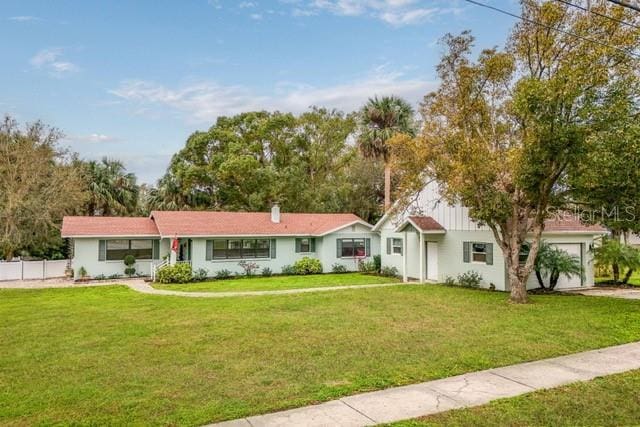 single story home with a front yard, fence, a chimney, and an attached garage