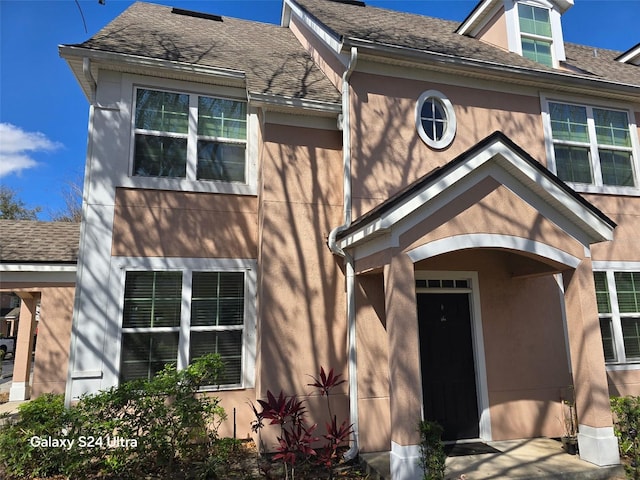 view of front facade featuring roof with shingles and stucco siding