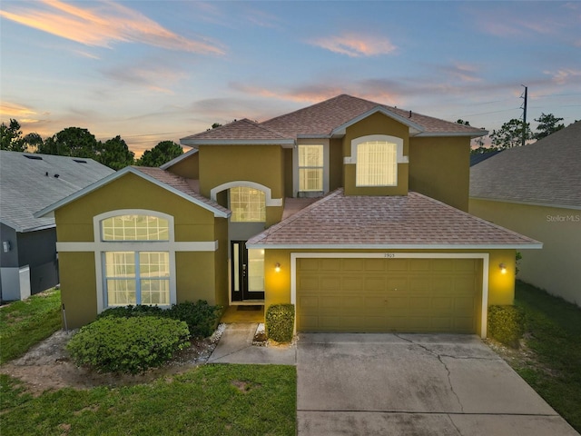 traditional-style home with a garage, concrete driveway, and stucco siding