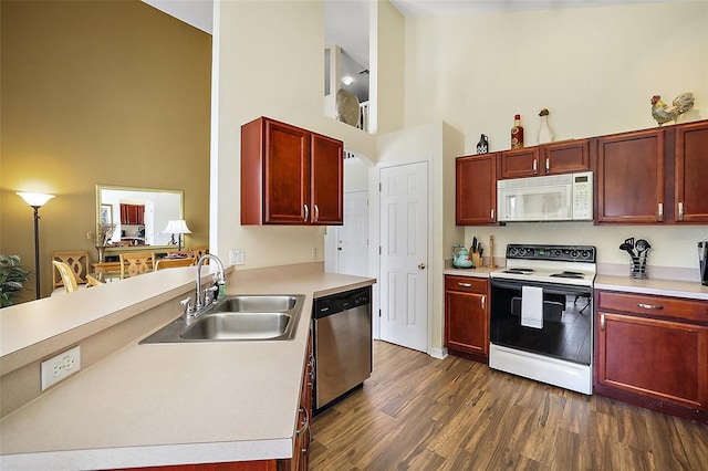 kitchen featuring light countertops, white appliances, a sink, and a towering ceiling