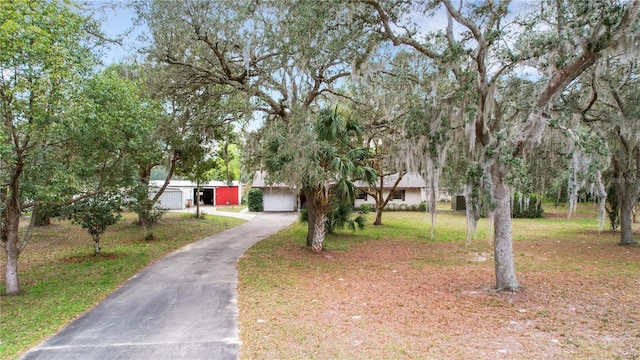 view of front of house featuring an attached garage, aphalt driveway, and a front yard