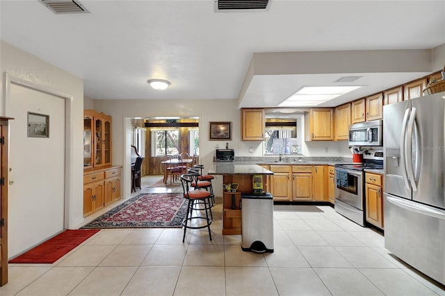 kitchen with stainless steel appliances, light tile patterned flooring, a sink, and visible vents