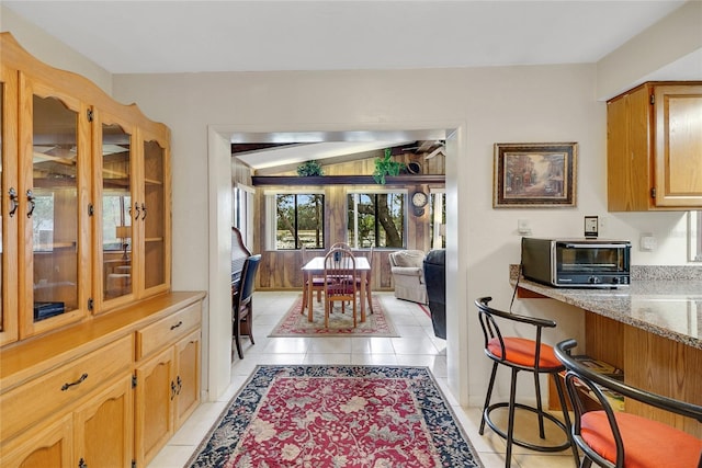 dining area featuring lofted ceiling, light tile patterned floors, and a toaster