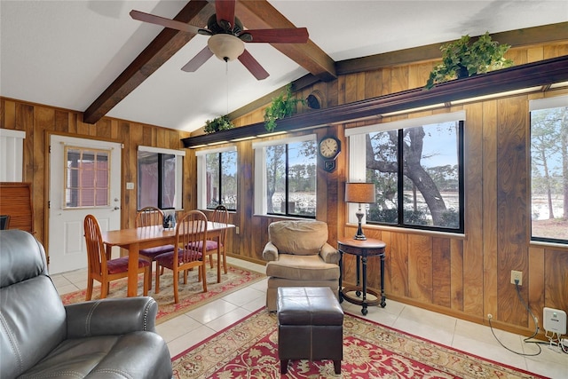 living area with lofted ceiling with beams, light tile patterned floors, ceiling fan, and wooden walls