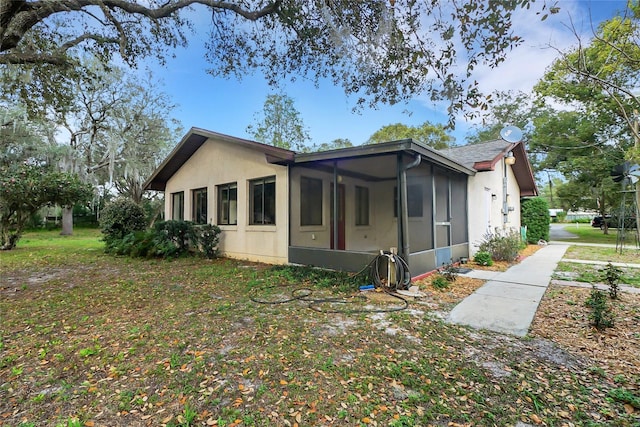 view of side of property with a sunroom and stucco siding