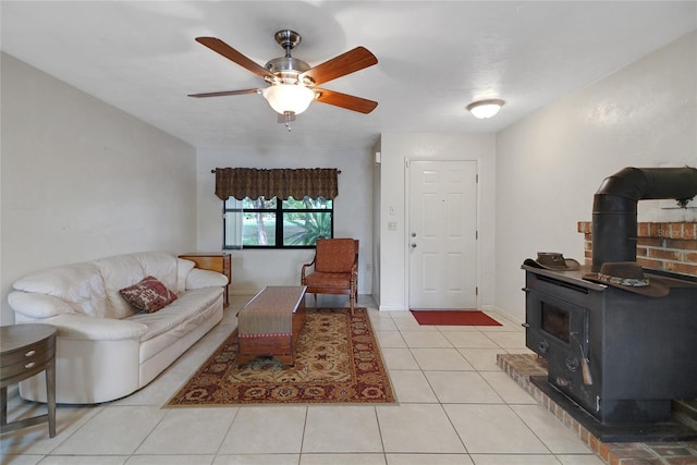 living area with a wood stove, light tile patterned floors, baseboards, and a ceiling fan