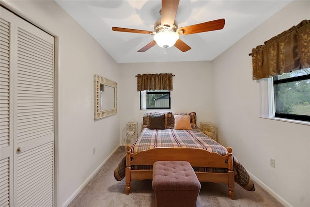 bedroom featuring baseboards, a closet, a ceiling fan, and light colored carpet