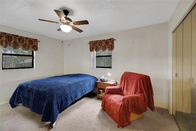 bedroom with a ceiling fan, baseboards, a closet, and light colored carpet