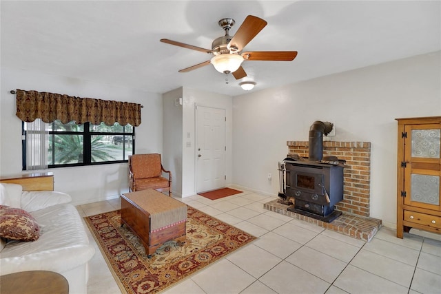 living room with a wood stove, baseboards, a ceiling fan, and light tile patterned flooring