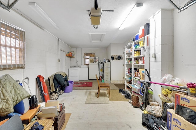 garage with concrete block wall, washing machine and dryer, gas water heater, and a garage door opener