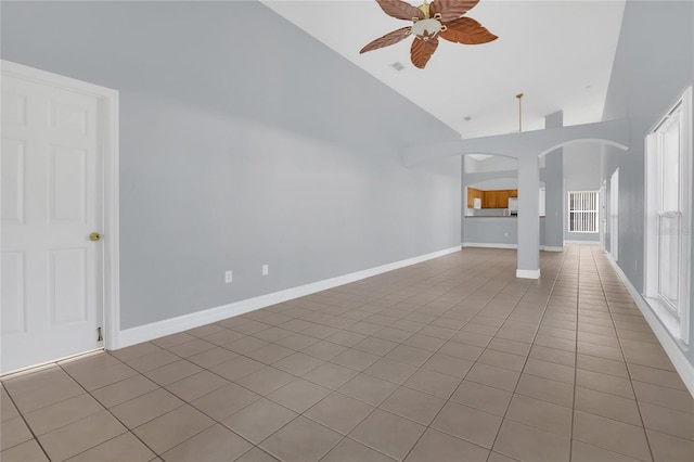 unfurnished living room featuring arched walkways, ceiling fan, high vaulted ceiling, tile patterned flooring, and baseboards