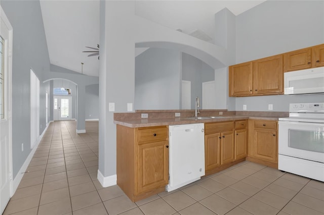 kitchen with arched walkways, light tile patterned floors, white appliances, a sink, and light countertops