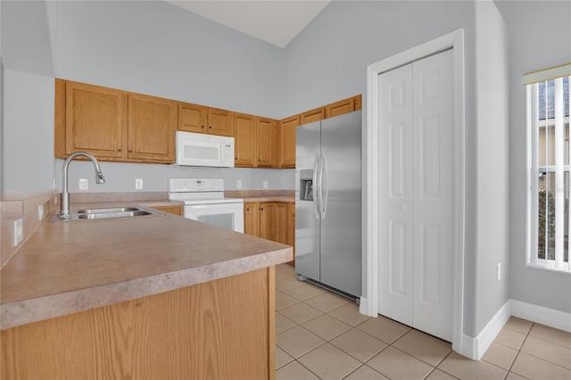 kitchen featuring light tile patterned floors, white appliances, a sink, baseboards, and light countertops