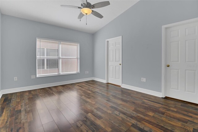 empty room with a ceiling fan, baseboards, vaulted ceiling, and dark wood-style flooring