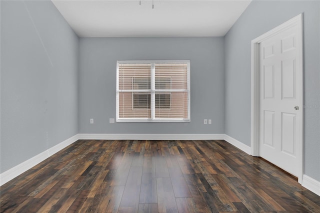 spare room with dark wood-type flooring and baseboards