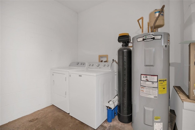 laundry room featuring water heater, laundry area, washing machine and clothes dryer, and concrete block wall