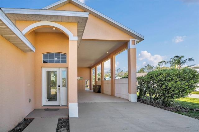 view of exterior entry featuring fence and stucco siding