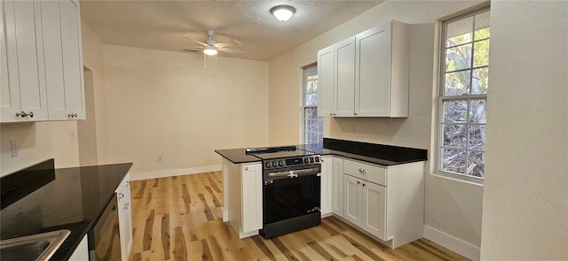 kitchen with stainless steel electric range oven, dark countertops, and white cabinets