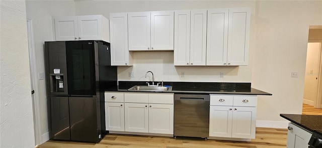 kitchen with dishwasher, black fridge, light wood-type flooring, white cabinetry, and a sink