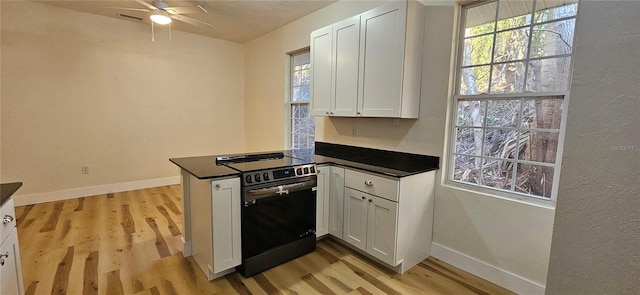 kitchen featuring dark countertops, light wood-type flooring, stainless steel electric range, and a peninsula