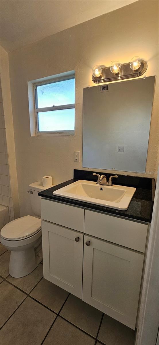 bathroom with toilet, visible vents, tile patterned flooring, and vanity