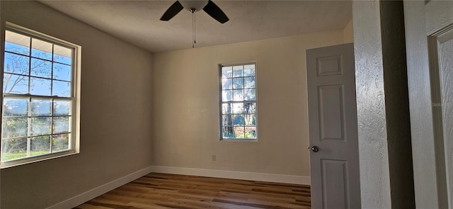 spare room with wood finished floors, a ceiling fan, and baseboards