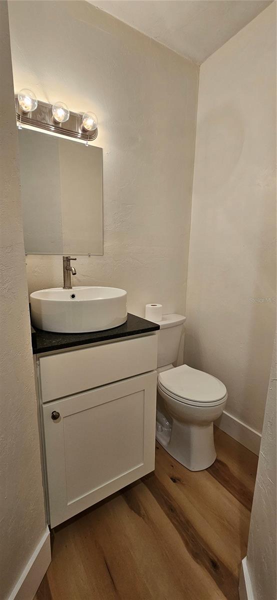 bathroom featuring baseboards, vanity, toilet, and wood finished floors
