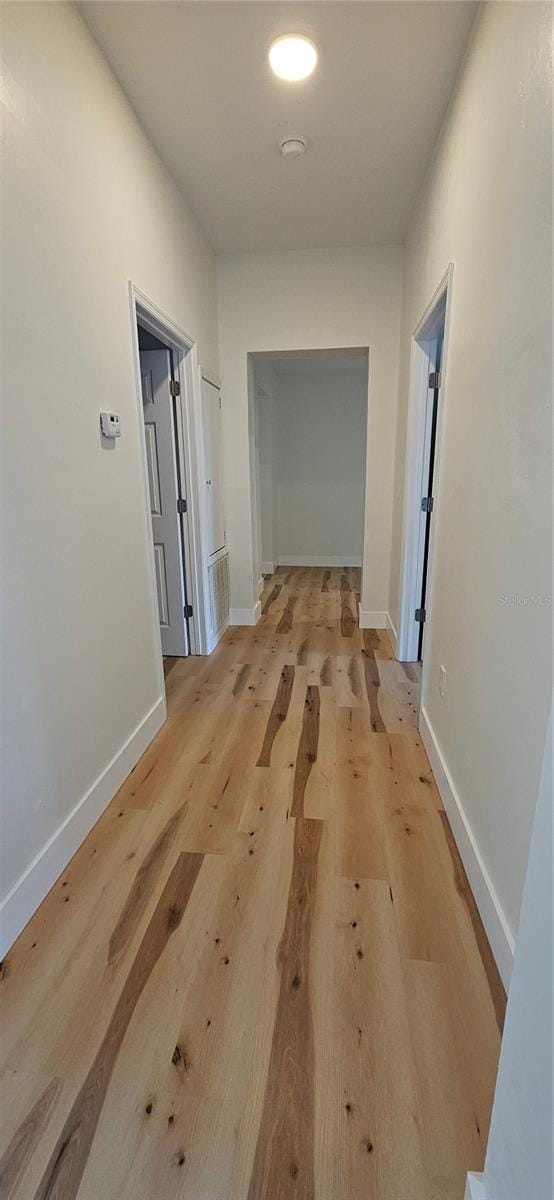 hall featuring light wood-type flooring and baseboards