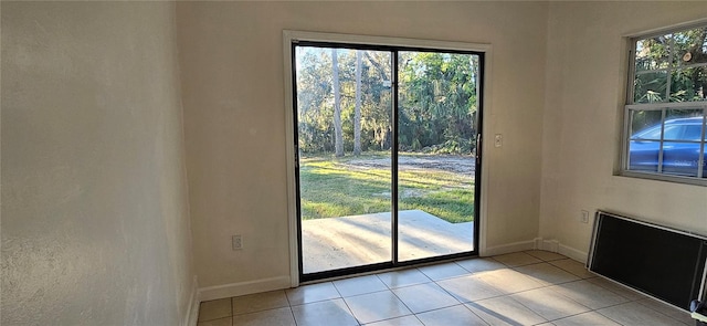 doorway with light tile patterned flooring and baseboards