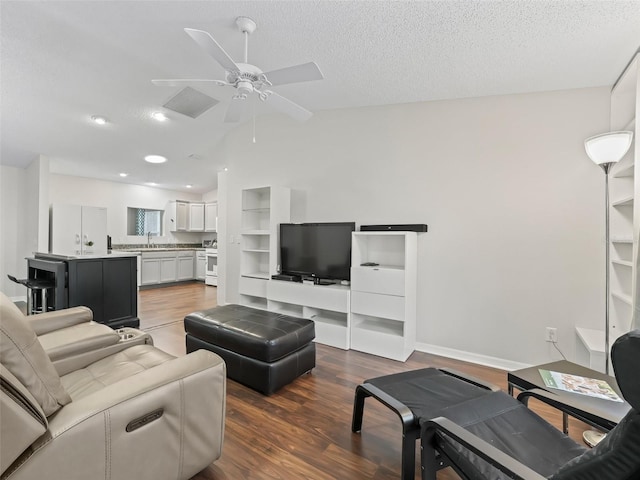 living room with a textured ceiling, dark wood-type flooring, vaulted ceiling, and a ceiling fan