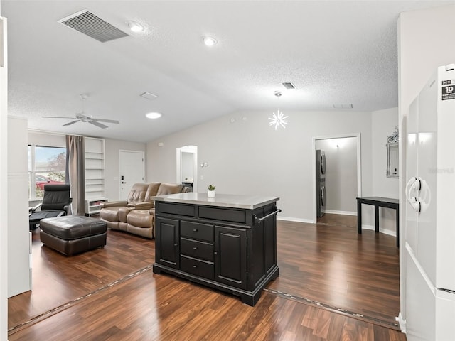 kitchen with visible vents, open floor plan, a center island, light countertops, and dark cabinetry