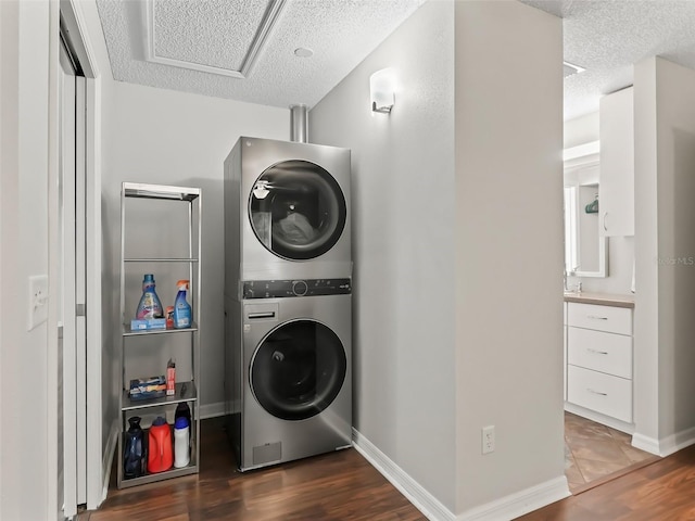 clothes washing area with stacked washer and dryer, laundry area, dark wood finished floors, and a textured ceiling