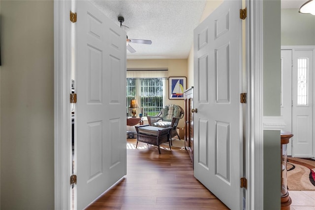 entryway featuring a textured ceiling, wood finished floors, a ceiling fan, and a healthy amount of sunlight